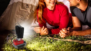 a LED work in front of two people next to a tent