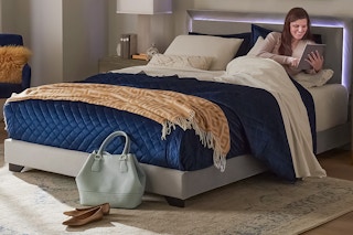 Lifestyle image of women laying in Hillsdale LED Queen Bed reading a book (Walmart.com)