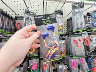 hand holding a pair of blue ear buds with a rainbow strap