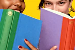 Lifestyle image of 2 people with books up to their face