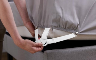 a bed sheet holder being put on a bed