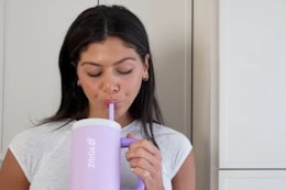 a woman using a purple tumbler