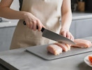 a person cutting up chicken on a titanium cutting board