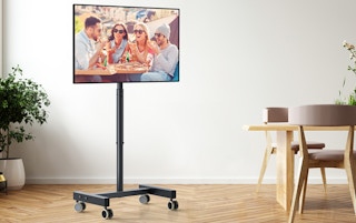 a TV on a rolling TV stand next to dining table