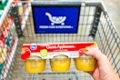 hand holding a pack of kroger applesauce over shopping cart