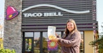 a person standing outside of taco bell with a mexican pizza