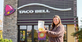 a person standing outside of taco bell with a mexican pizza