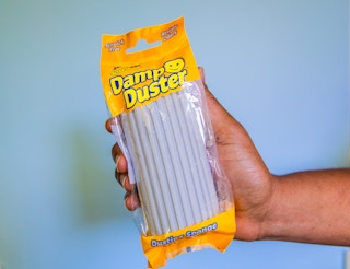 Hand holding a scrub daddy damp duster in its original packaging