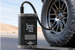  Aneson Tire Inflator Portable Air Compressor sitting on the ground next to a vehicle tire.