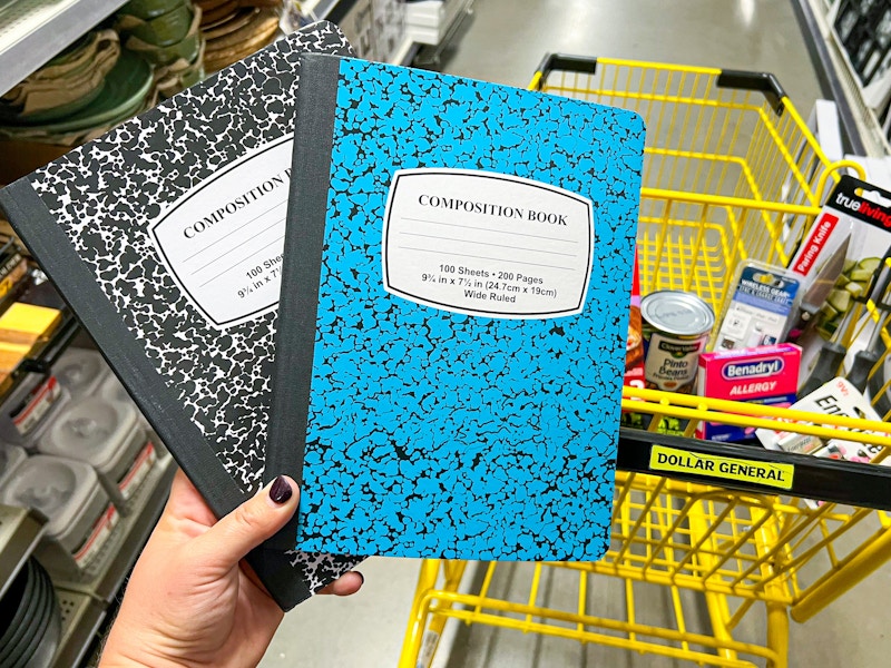 Someone holding up two composition notebooks next to a cart at Dollar General