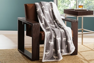 Lifestyle image of the Eddie Sherpa Throw Blanket in the Elk print on accent chair
