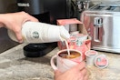 a woman pouring creamer into a cup of coffee with the starbucks kcups on counter 