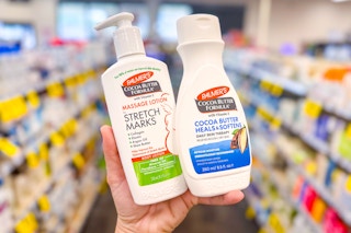 person holding 2 bottles of palmers cocoa butter lotion in an aisle