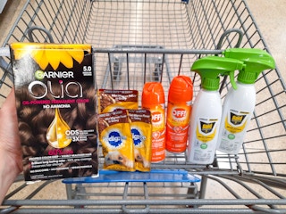 Garnier Olia Hair Color product held over Walmart shopping cart filled with Pedigree, Off, and Raid products