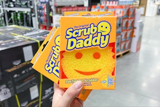 a person holding up two scrub daddy sponges in a store