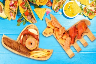 A sombrero-shaped wood tray and a donkey-shaped wood tray are covered in and surrounded by snacks.