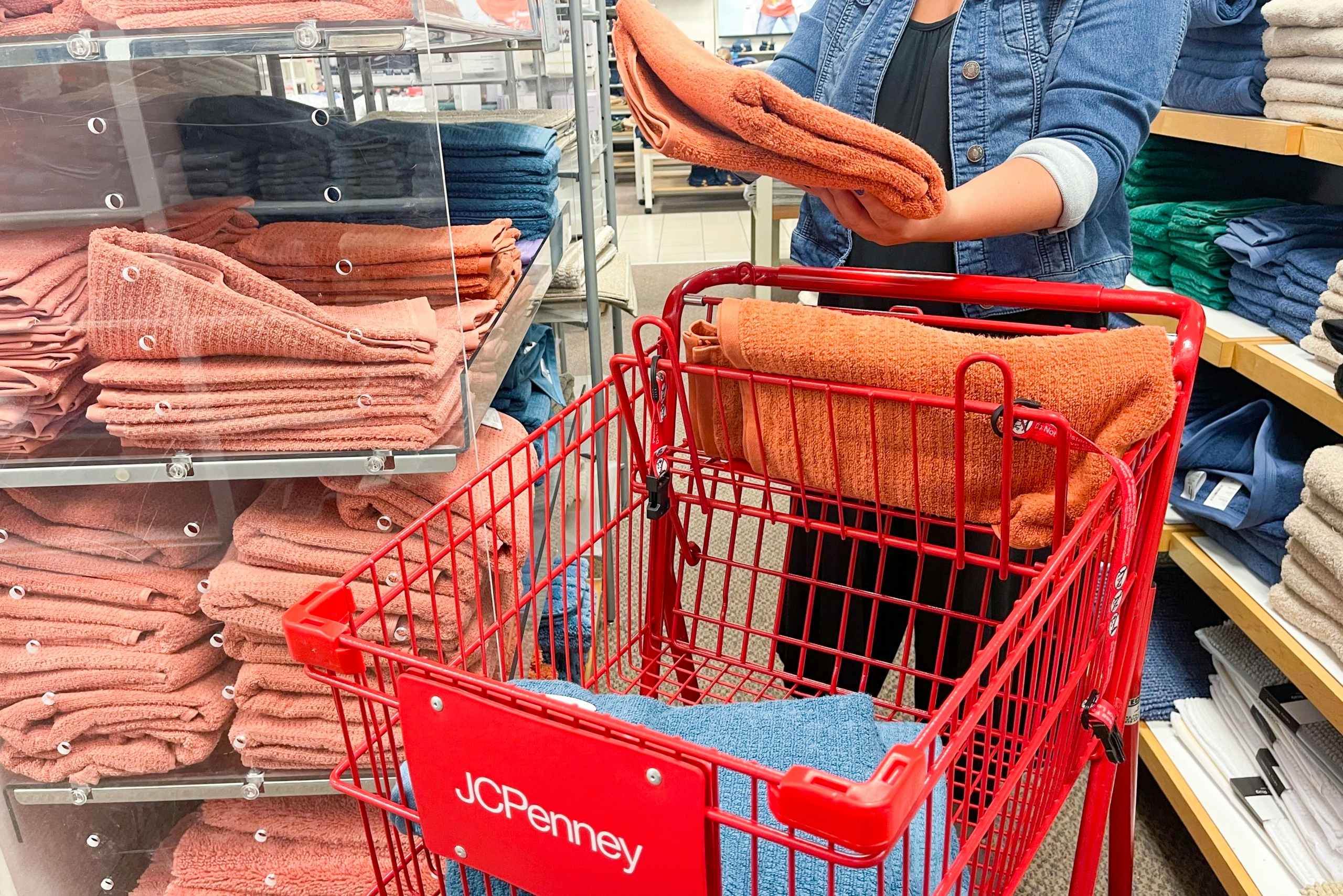 A woman shopping for towels at JCPenney with a cart.