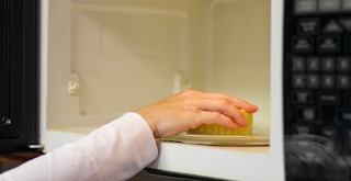 a person scrubbing the inside of a microwave
