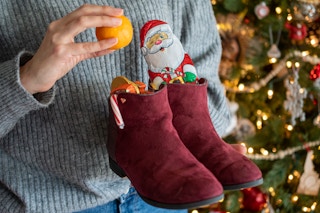 A person putting an orange into a shoe fulled with candy