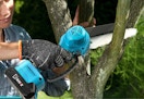 person using a blue mini chainsaw on a tree