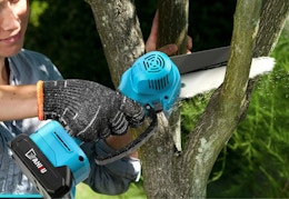 person using a blue mini chainsaw on a tree
