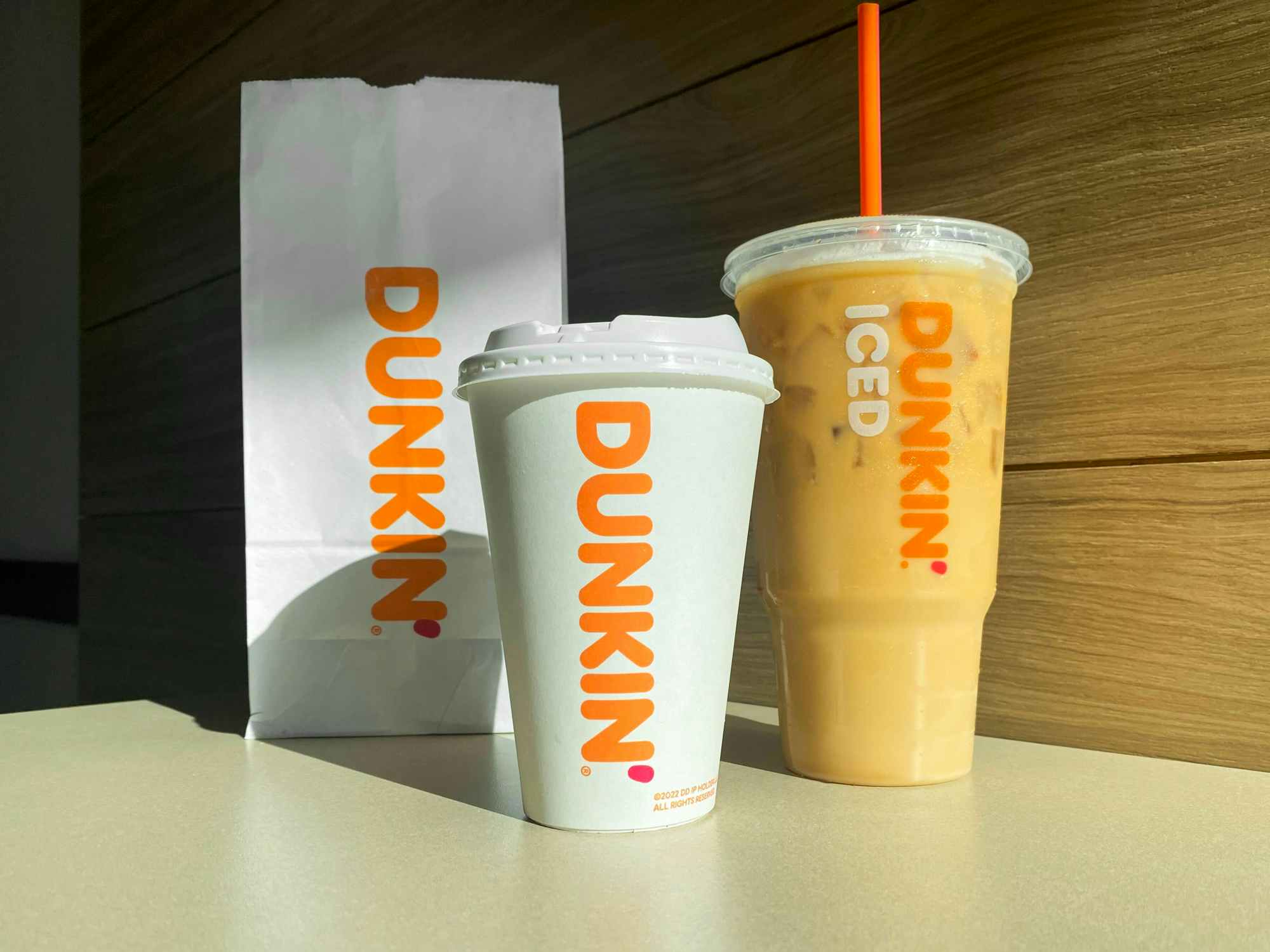 pumpkin spice drinks and a bag from Dunkin on a table