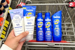 a hand holding up sunscreen in front of a cart of coppertone sunscreen