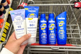 a hand holding up sunscreen in front of a cart of coppertone sunscreen