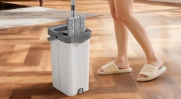 a person dipping a flat mop into a bucket 