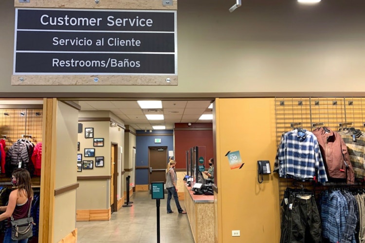 Person standing at REI customer service counter with clothing displays in front