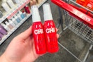 person holding 2 chi heat protection sprays by a cart