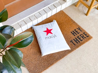 A Macy's online order package on a mat outside a front door.