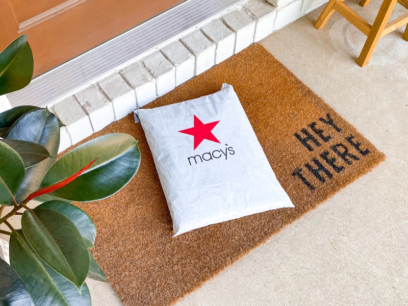 A Macy's online order package on a mat outside a front door.
