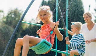 stock photo of girl playing on plum play metal swing set