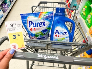 hand holding sales tag in front of shopping cart with Purex pacs and laundry detergent inside
