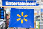 Walmart bag held up in front of Entertainment sign in store