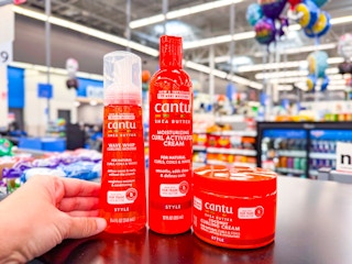 hand holding a bottle of cantu hair care with two others on table at walmart