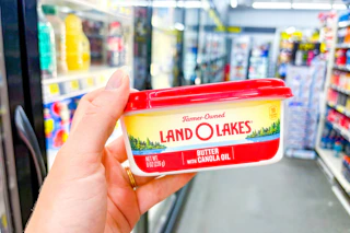 hand holding a tub of land o lakes spreadable butter