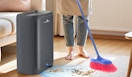 a person sweeping dirt into an automatic dustpan
