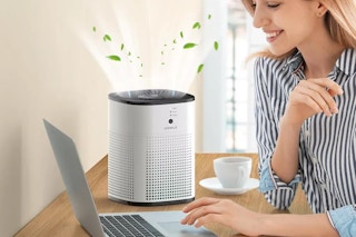 women typing on laptop next to an air purifier