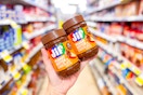 hand holding two jif chocolate peanut butter spreads
