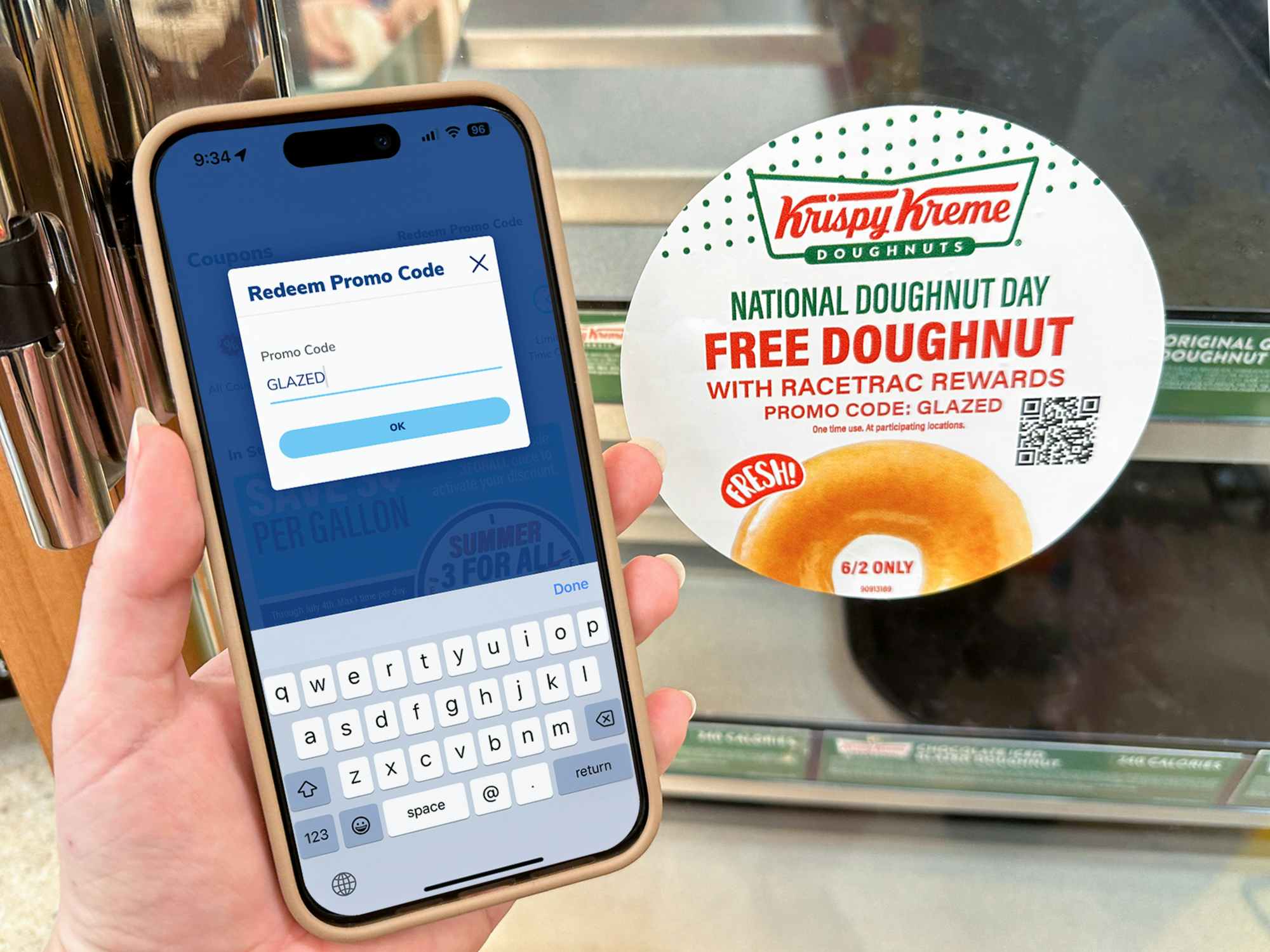 Someone holding a phone next to the RaceTrac Krispy Kreme donut display with a sign advertising the National Doughnut Day offer with ...