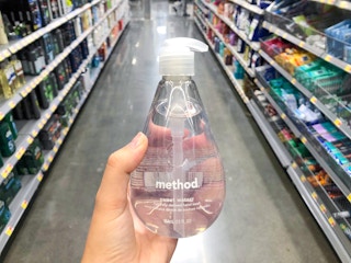 hand holding bottle of soap in front of aisle