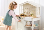 child playing with a white wooden play kitchen