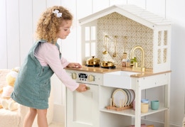 child playing with a white wooden play kitchen