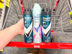 person holding 3 degree dry spray deodorants over a cart