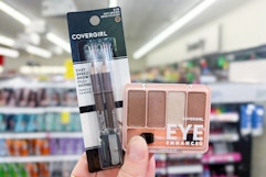 person holding covergirl eyeliner and eyeshadow
