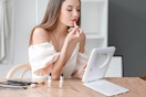 a woman putting on makeup in front of a mirror