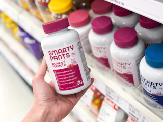 hand holding vitamin bottle in front of shelf at target