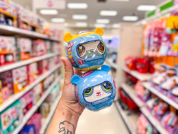 hand holding 2 littlest pet shop plush pets in a target aisle
